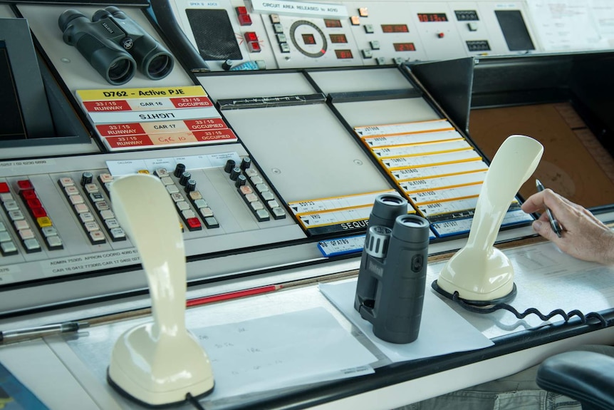 Two-way radios, binoculars, radar screens and instrument panels on the air traffic control desk in the Cairns Airport tower.