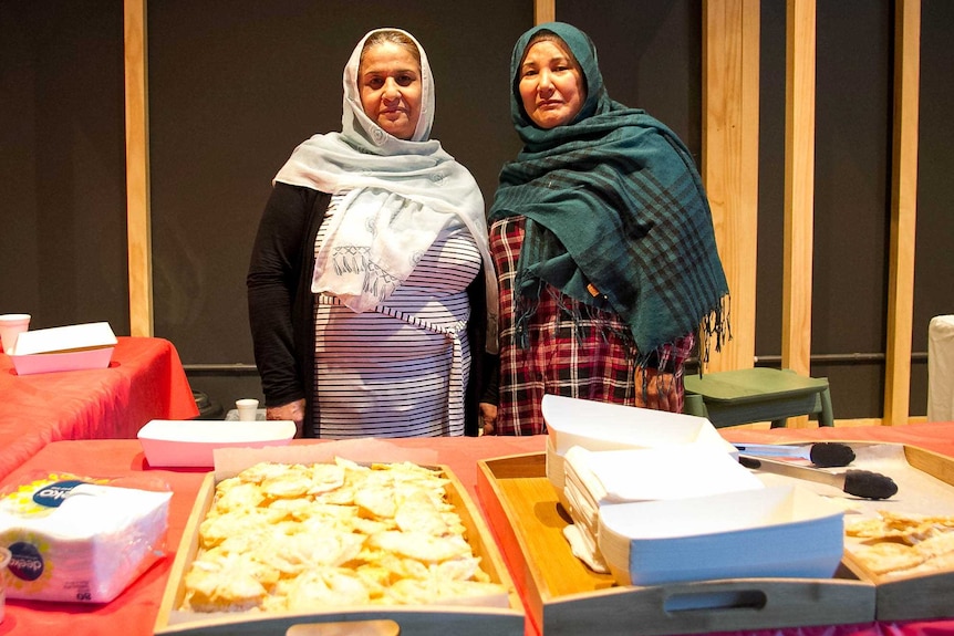 Two women watch over a food stall at refugee week in Toowoomba.