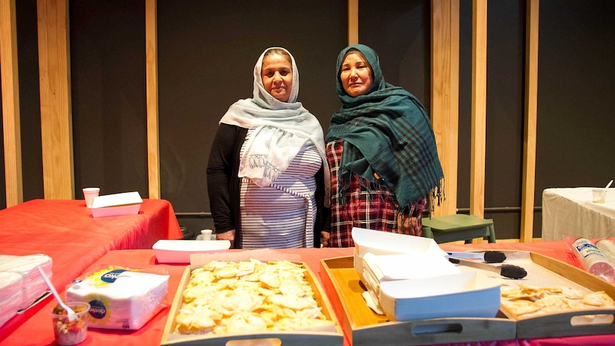 Two women watch over a food stall at refugee week in Toowoomba.