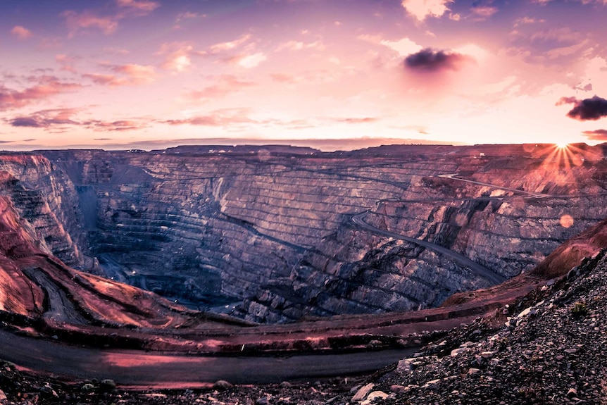 The sun rises over an open pit gold mine