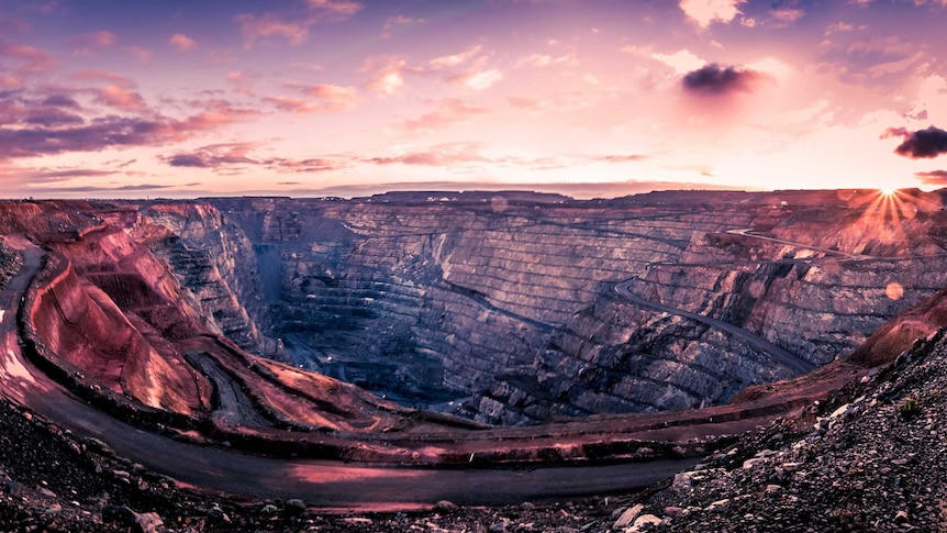 The sun rises over an open pit gold mine.