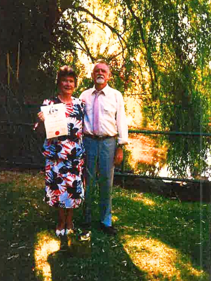 a man and a woman standing in front of a lake.