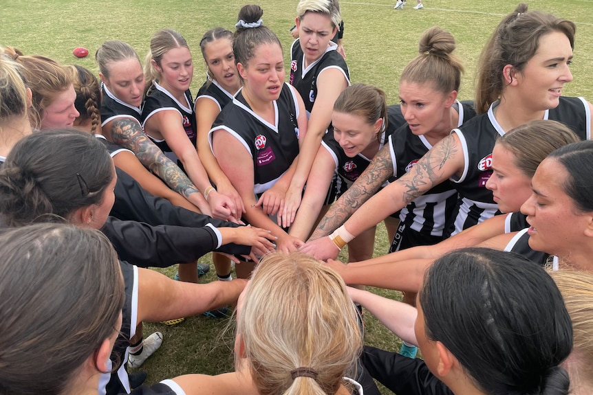 A group of footballers huddle up before a game