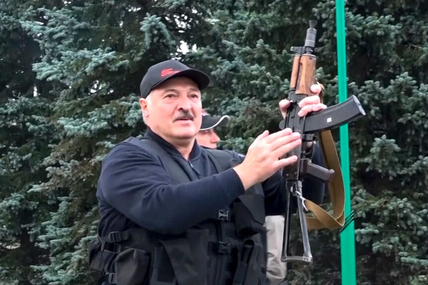 Lukashenko holds up  a rifle.