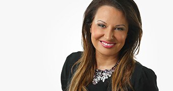 Larissa Behrendt looks into the camera, smiling, standing against a white background.