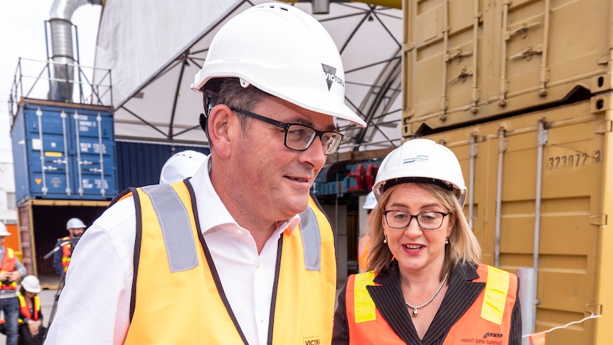 Daniel Andrews and Jacinta Allan side-by-side at a press conference around shipping containers.