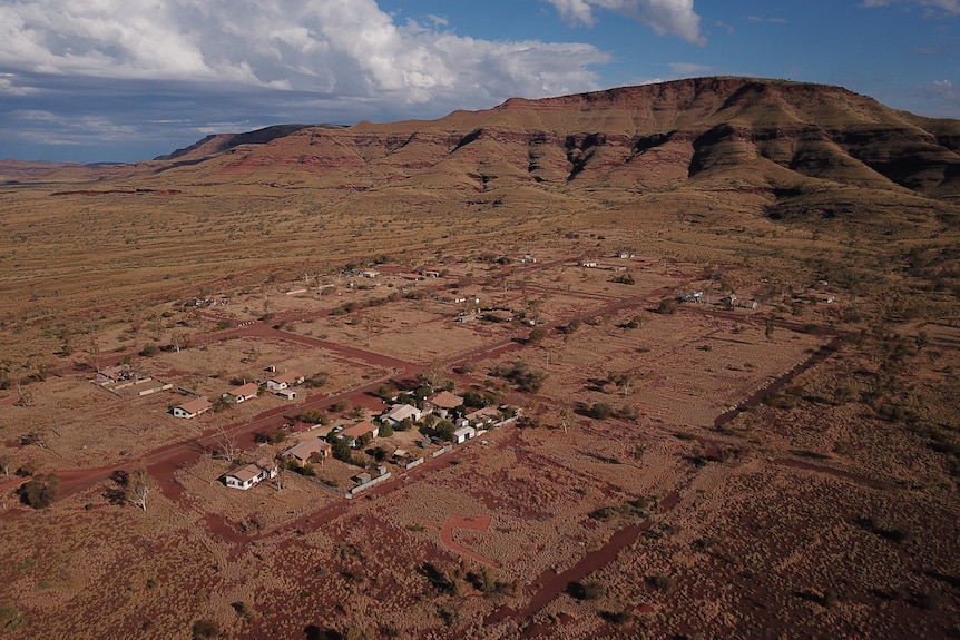 An aerial view of several homes in bushland, with a mountain range in the background.