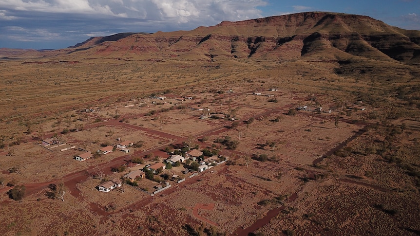 An aerial view of several homes in bushland, with a mountain range in the background.