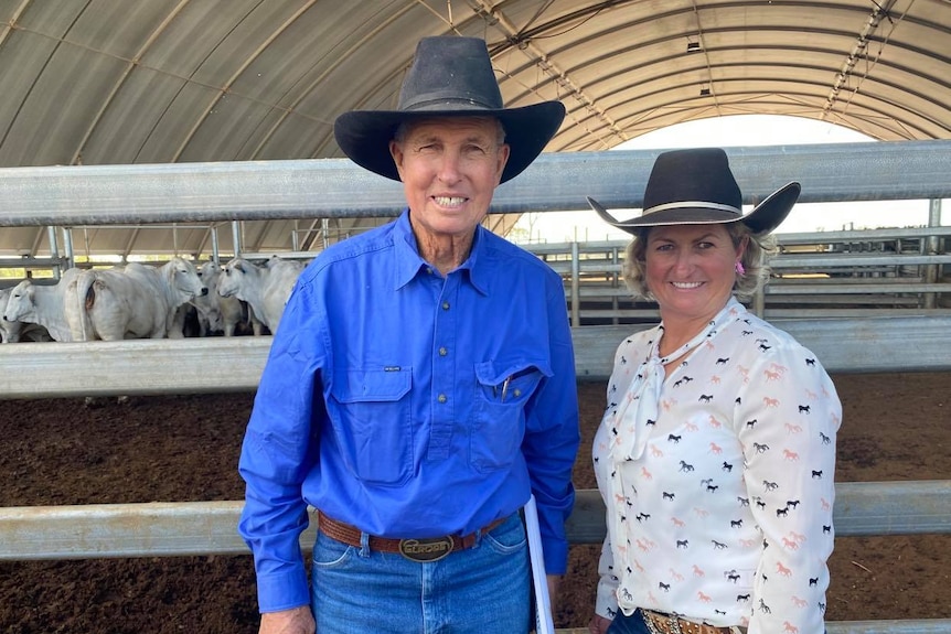 a an older man in a vblue shirt with a woman, bioth wearing cattle style hats 