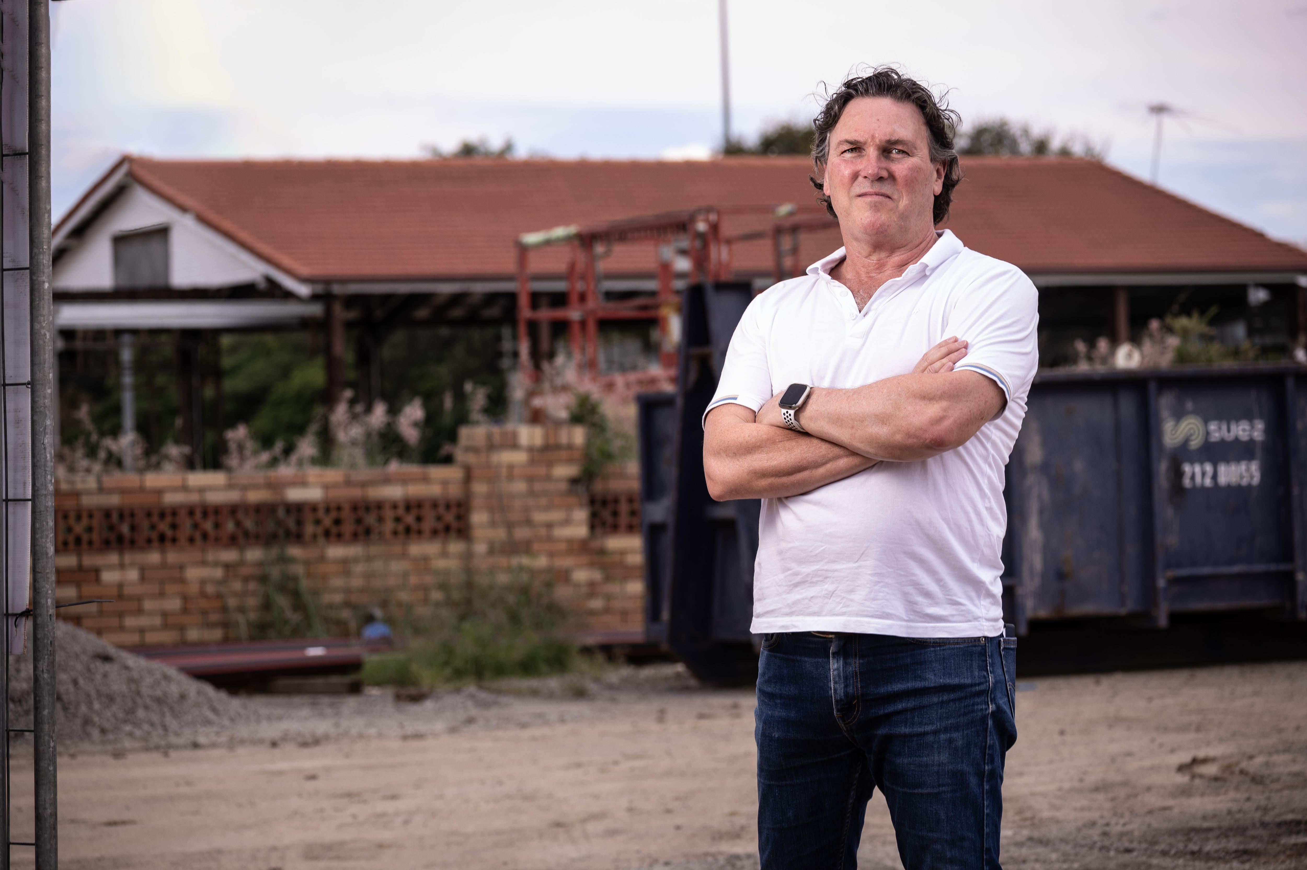 A man with crossed arms in front of a construction site