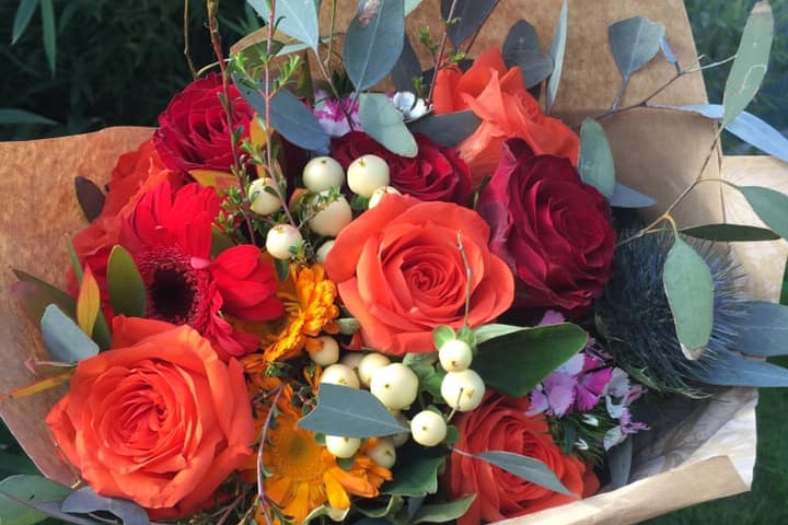 A bouquet of bright orange roses and colourful flowers.