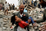 A man carries a young girl through rubble after an air strike in Yemen.