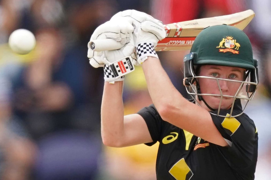 Beth Mooney completes her shot as she watches a white cricket ball fly away during a T20 against India.