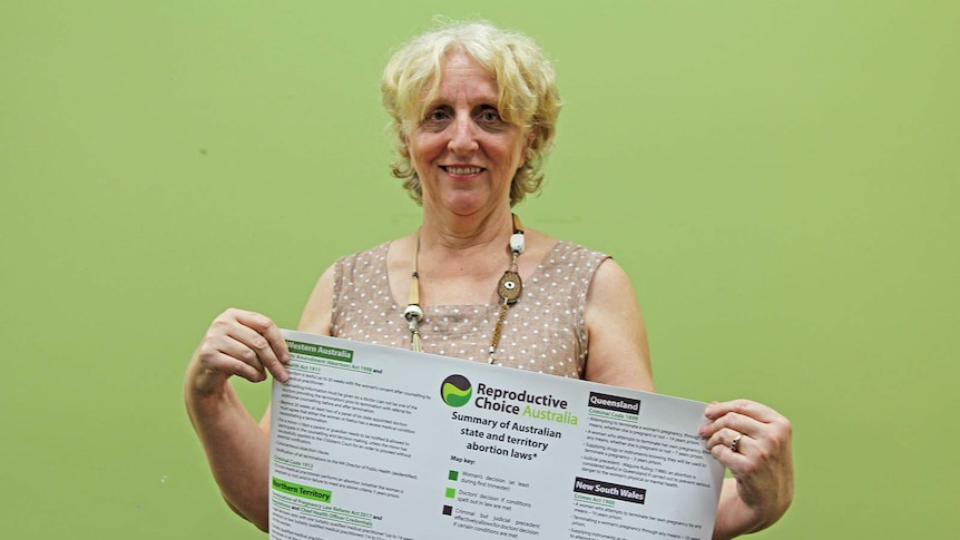 Women's reproductive right campaigner Robyn Wardle proudly holding a sign that maps out abortion laws in Australia.