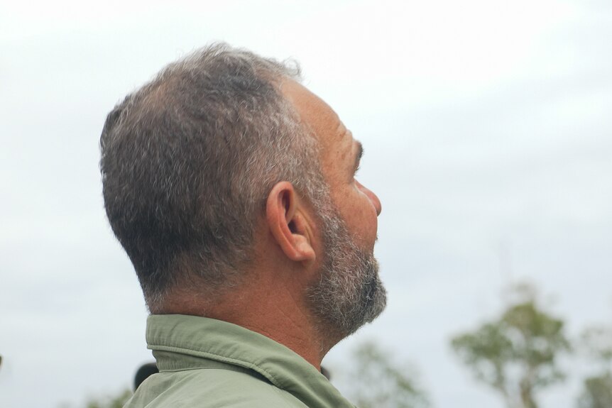 Brendan Waters looking at through frame at a tree at Toomelah, New South Wales, March 2024.