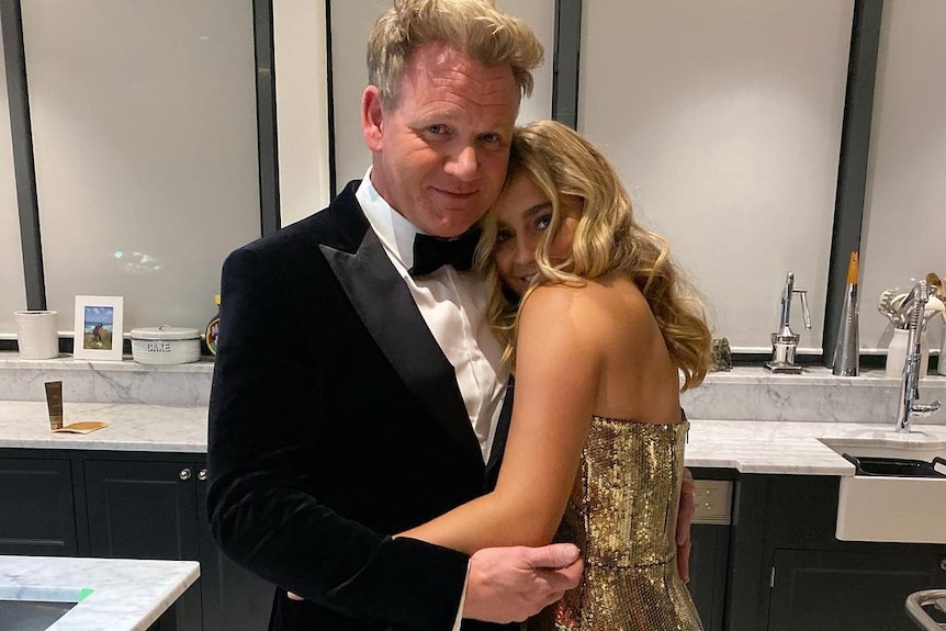 Gordon Ramsay dressed in a tuxedo, hugs is daughter Tilly who is wearing a gold dress.