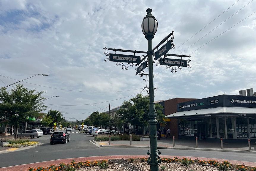 Ornate green street sign and lamp in foreground with warragul street in the background