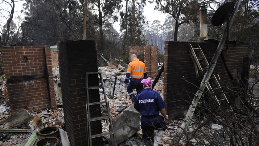 Forensic police sift through a burnt out house