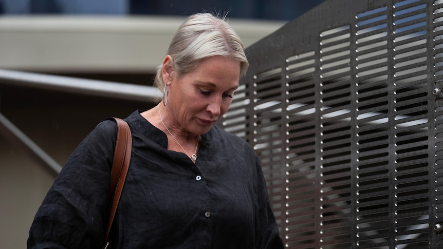 A woman with blonde hair looks down as she leaves a court building in Hobart.