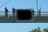 Men stand next to a banner on a highway overpass