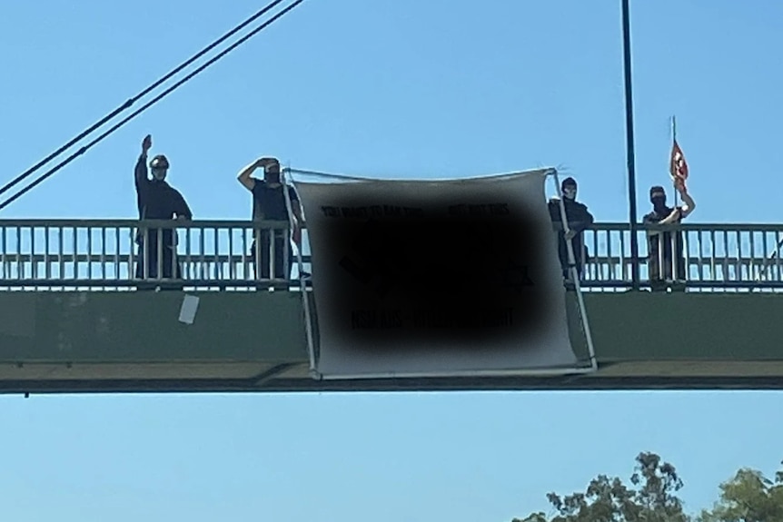 Men stand next to a banner on a highway overpass