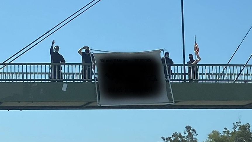 Men stand next to a banner on a highway overpass