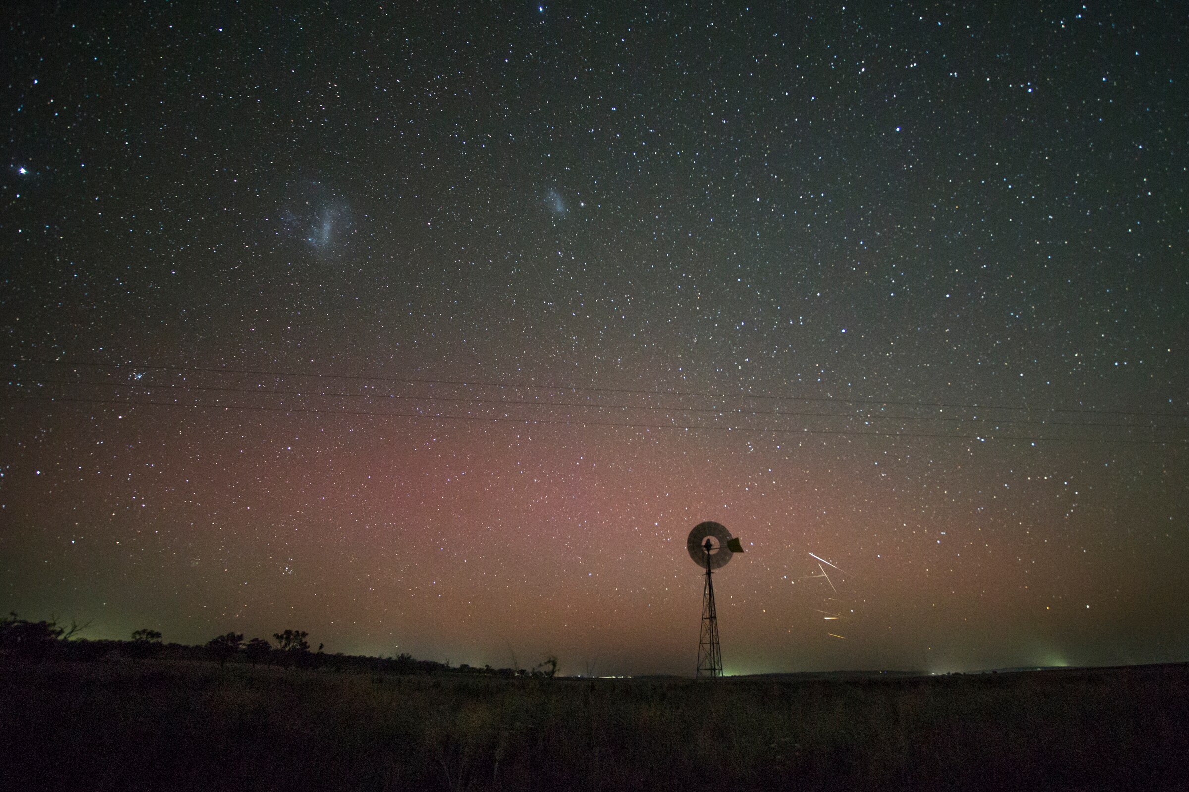Um leve tom rosa e verde é visto contra um céu com um moinho de vento no horizonte.