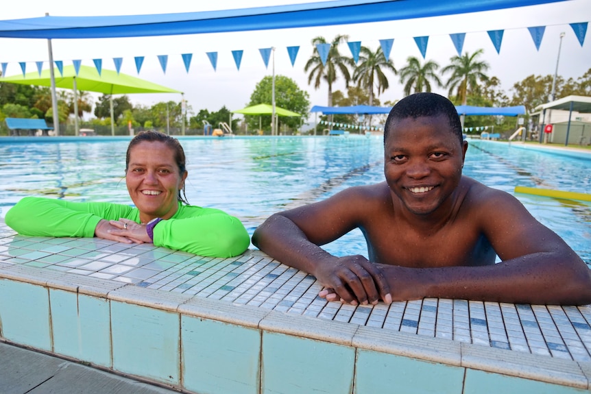 a man and woman in a swimming pool smile at the camera while resting their arms on the side of the pool 