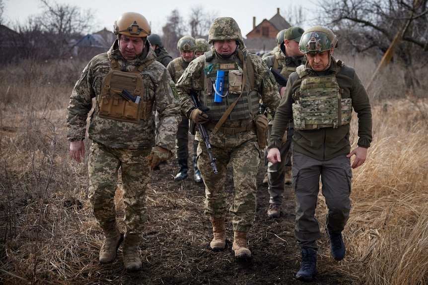 Ukrainian President Volodymyr Zelenskyy walks with service members of the country's armed force.