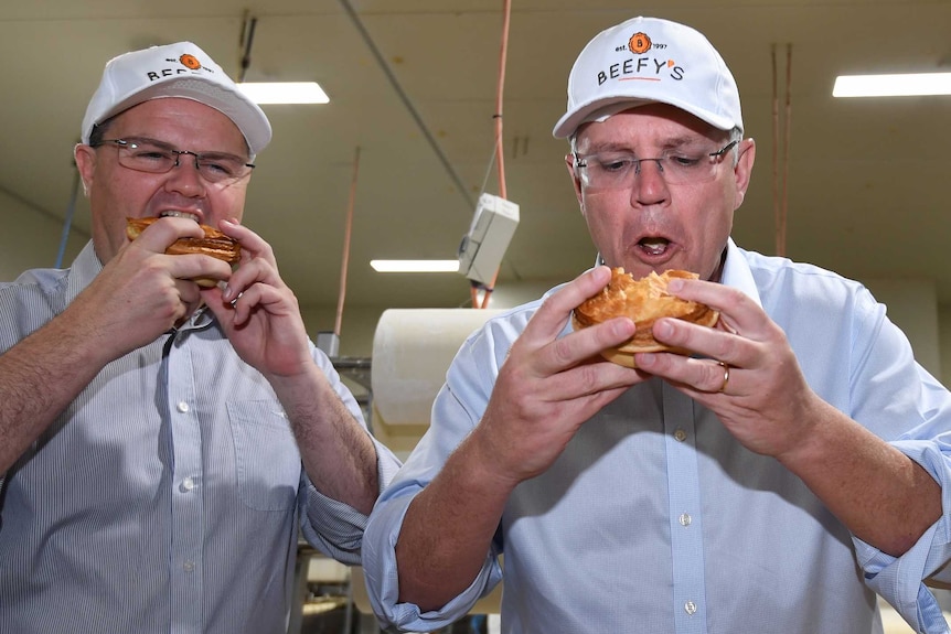 Scott Morrison and the member for Fairfax Ted O'Brien eat pies during a visit to the Beefy's Pies factory.