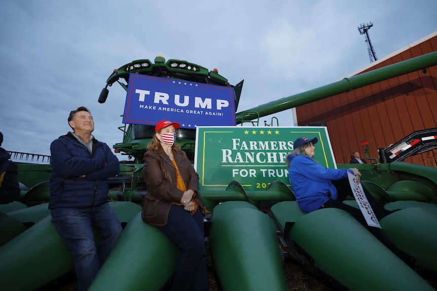 Farmers sit on a big green tractor at a Trump rally