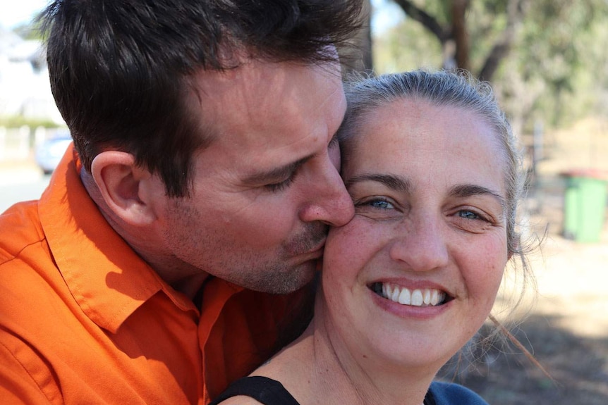 Kerri Brown being kissed on the cheek by her fiance Brett Halford, smiling.
