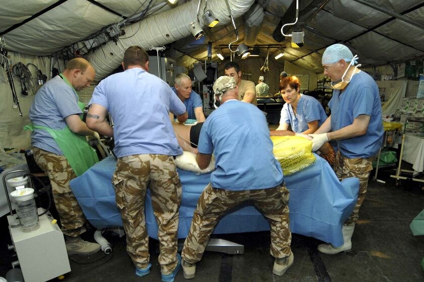 Picture of a military clinic with a team of surgeons operating on a patient  