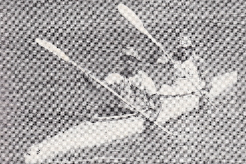 An old black and white phot of two men in a canoe