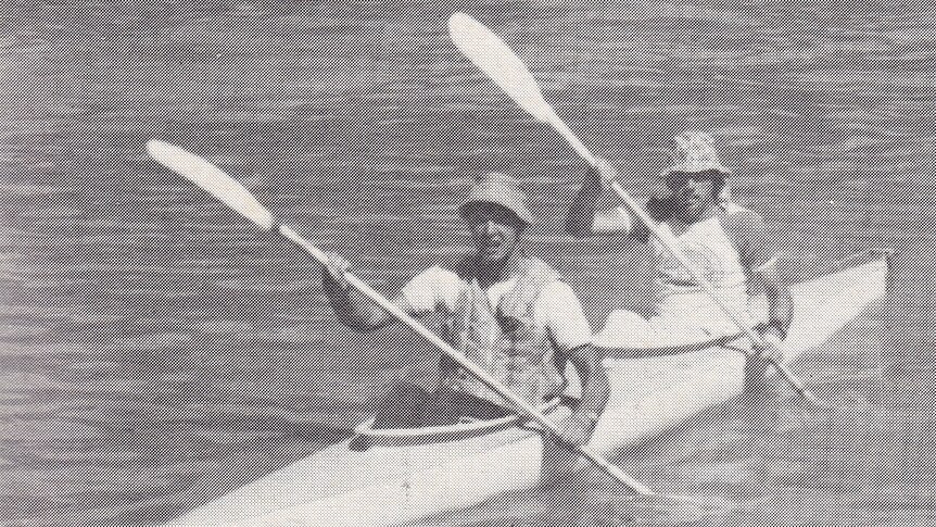 An old black and white phot of two men in a canoe