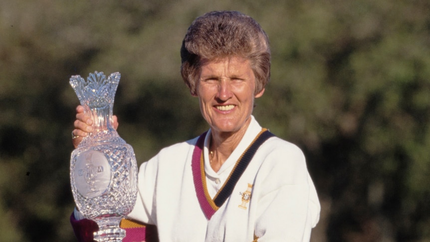 A woman holds a gold trophy after winning a tournament