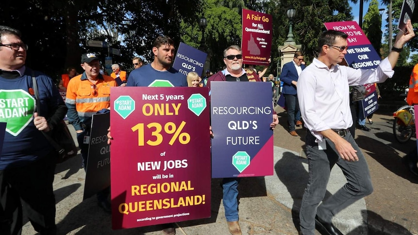 A rally of people holding placards with: Fair go for all Queenslanders