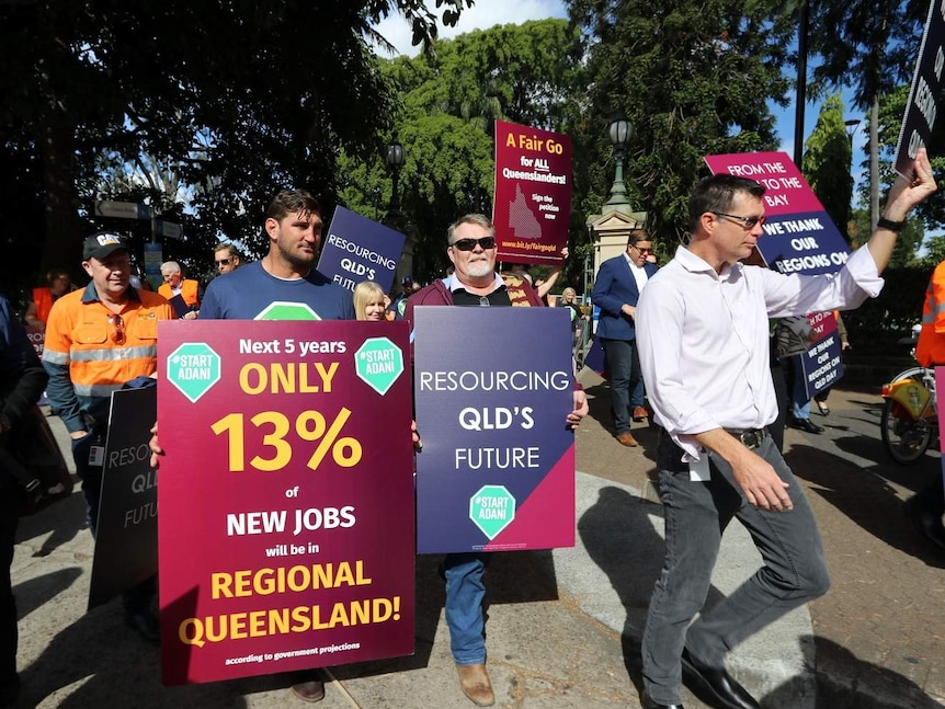 A rally of people holding placards with: Fair go for all Queenslanders