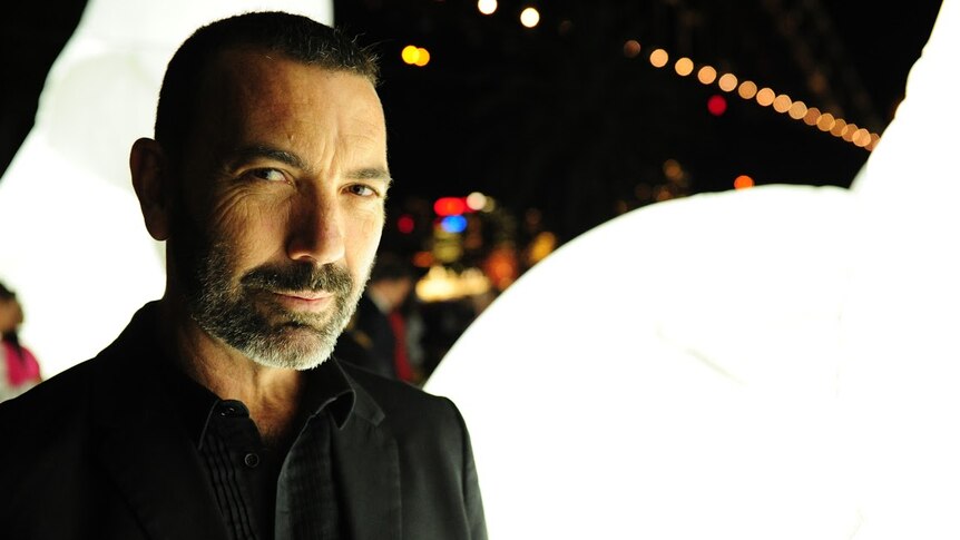 Producer Paul Mac stands alongside a bright white globe light