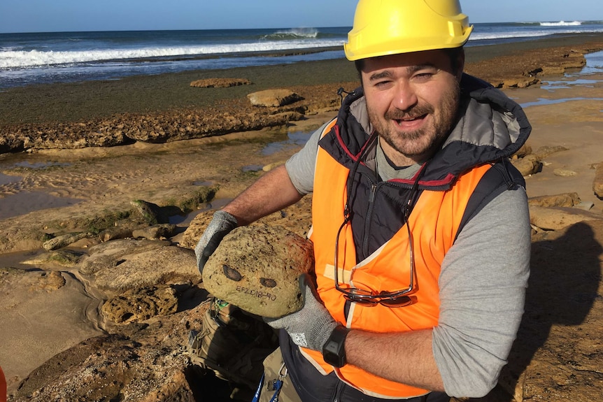 Ben Francishelli holds rock that contains ancient whale ribs