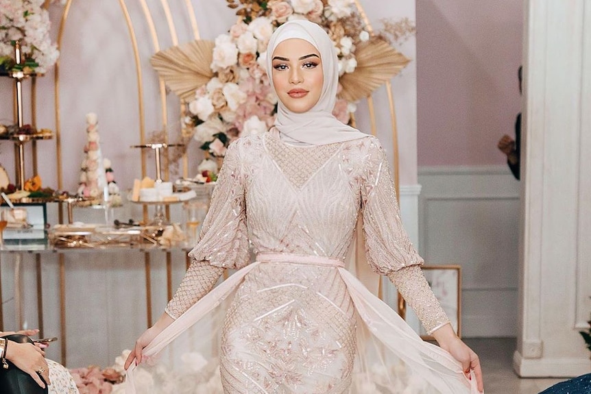 A woman in a pink dress and hijab.