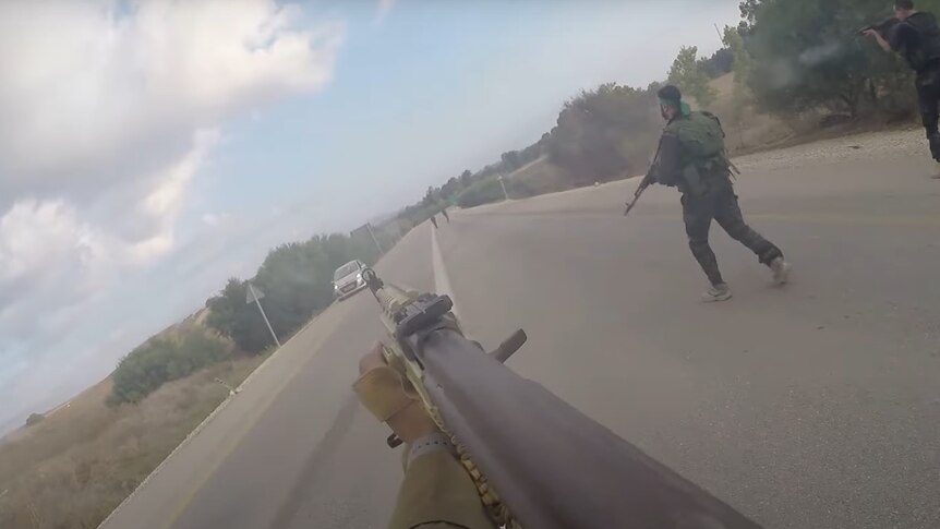 A screenshot from body camera footage showing a gun pointed down a road as a car approaches. 