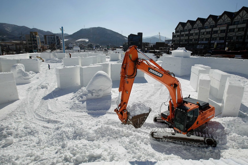 Workers toil on a large ice sculpture at the Pyeongchang Olympic Plaza ahead of the Winter Games.