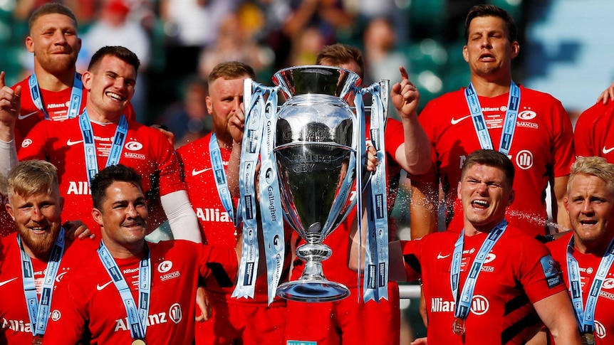 Saracens players, wearing premiership medals, left the large Premiership Rugby cup.
