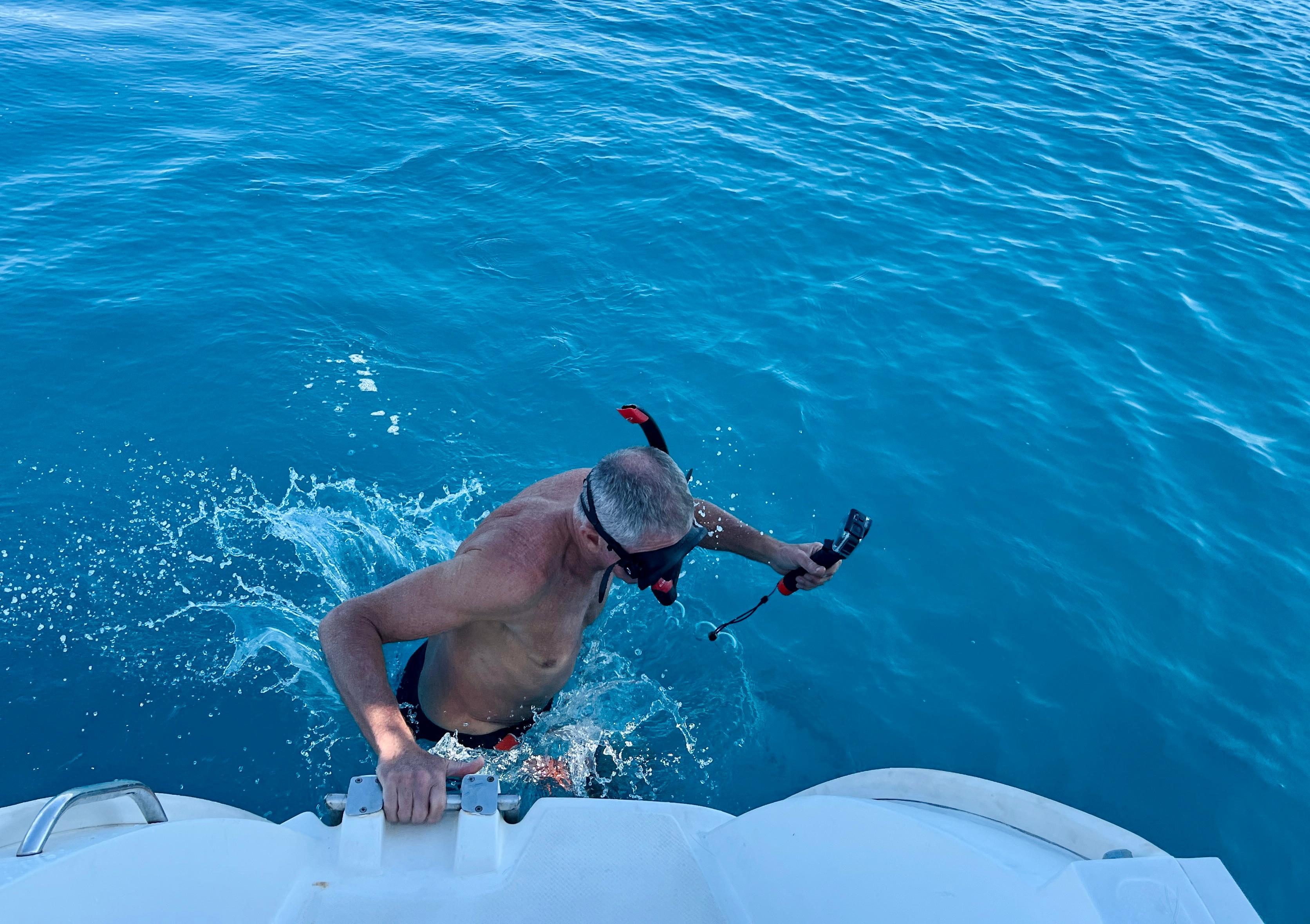 A man wearing a snorkel partially submerged in blue water