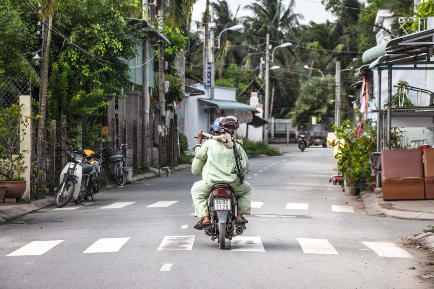 Nguyen Quoc Thanh rides away with shovel on shoulder