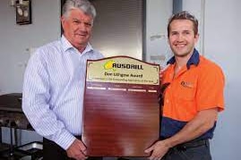 A man presenting an award to a junior worker. 