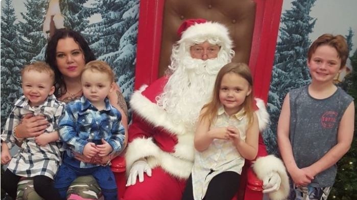 A dark-haired woman, four children and Santa Claus posing for a photo.