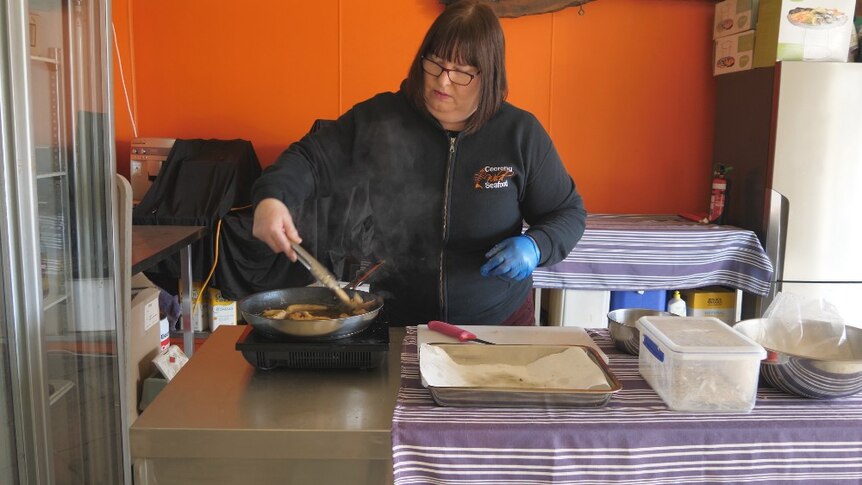 Tracy Hill stir frying strips of carp in a saucepan.