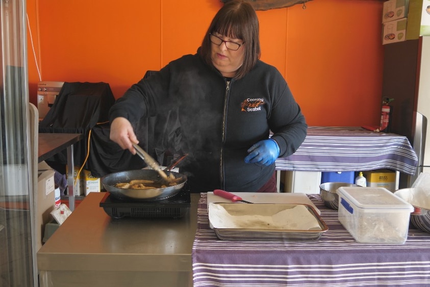 Tracy Hill stir frying strips of carp in a saucepan.